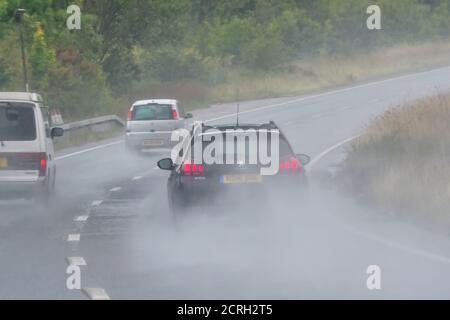 Fahrer, die Autos auf einer zweispurigen Fahrbahn bei starkem Regen mit schlechter Sicht in England, Großbritannien, fahren. Schlechtes Wetter und nasse, gefährliche Straße beim Regen. Stockfoto