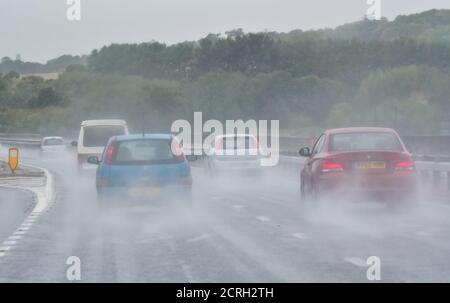 Fahrer, die Autos auf einer zweispurigen Fahrbahn bei starkem Regen mit schlechter Sicht in England, Großbritannien, fahren. Schlechtes Wetter und nasse, gefährliche Straße beim Regen. Stockfoto