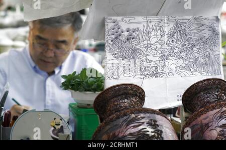 (200920) -- PEKING, 20. September 2020 (Xinhua) -- Zhong Liansheng entwirft die Muster für den Cloisonne-Körper in der Pekinger Emaille-Fabrik in Peking, Hauptstadt von China, 15. September 2020. In China stellt "Jingtailan" eine besondere Cloisonne aus Kupfer und Porzellan dar. Eingeführt aus den arabischen Ländern während der Yuan-Dynastie (1271-1368) und immer beliebter während der "Jingtai" Jahre der Ming-Dynastie (1368-1644), verwendet die Jingtailan Cloisonne rotes Kupfer als Körper, mit Mustern mit Kupferdrähten strukturiert und mit Emaille Glasur gemalt. Die Herstellung muss Dutzende von Verfahren durchlaufen Stockfoto