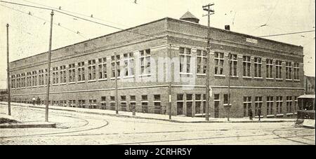 . Elektrische Eisenbahn Zeitschrift . Omaha Carhouse – A Corner of the Employees Reading Room Rail ist 7 ft. 2 Zoll in Länge, an einem Ende durch einen 2-Zoll-Stahlstift schwenkbar, der 18 Zoll in den Boxensockel ragt. Der obere Teil des Stiftes ist horizontal gebogen, so dass er mit dem abnehmbaren Schienenabschnitt verschraubt werden kann. Durch Loslassen der Sperrvorrichtung am gegenüberliegenden Ende kann der wieder bewegliche Schienenabschnitt aus dem Weg geschwenkt werden, wodurch das Rad in die Grube fallen gelassen werden kann. Durch die Bereitstellung eines Winkels Omaha Carhouse – Innenansicht von First-FloorEntrance Auto Clearance, und die Strecken jenseits der besonderen Stockfoto