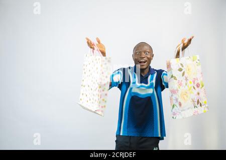 Afroamerikanischer Mann hält Pakete und fühlt sich aufgeregt Stockfoto