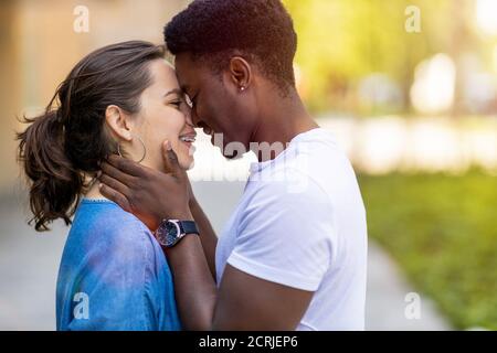 Multirassische junge Paar küssen im Freien Stockfoto