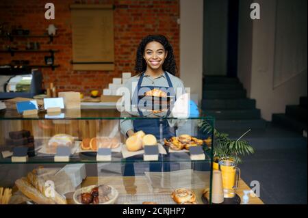 Weibliche Barista hält Teller mit Croissant im Café Stockfoto