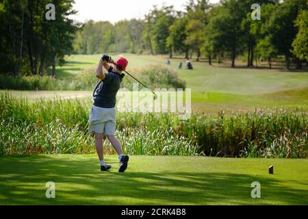 Rückansicht des männlichen Golfers mittleren Alters, der auf sonnigem Golf fährt Kurs Stockfoto