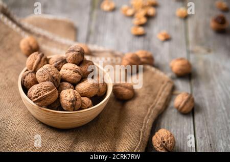 Ganze Walnüsse in einer Schüssel und Jute-Beutel auf rustikalem alten Holztisch. Gesunde Bio-Lebensmittel, Bio-Viands, natürlicher Hintergrund. Kopieren Sie Platz für Ihre Werbung Stockfoto
