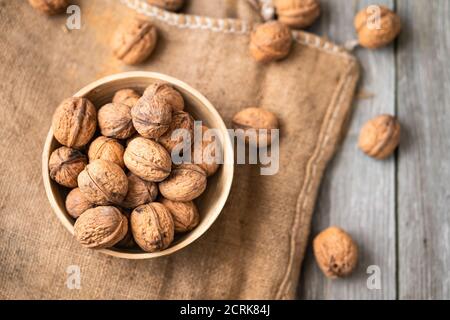 Ganze Walnüsse in einer Schüssel und Jute-Beutel auf rustikalem alten Holztisch. Gesunde Bio-Lebensmittel, Bio-Viands, natürlicher Hintergrund. Kopieren Sie Platz für Ihre Werbung Stockfoto