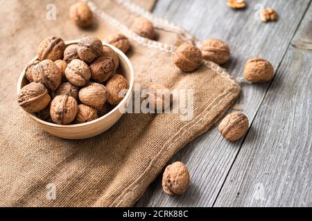 Ganze Walnüsse in einer Schüssel und Jute-Beutel auf rustikalem alten Holztisch. Gesunde Bio-Lebensmittel, Bio-Viands, natürlicher Hintergrund. Kopieren Sie Platz für Ihre Werbung Stockfoto