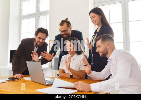Glückliche Firmenmitarbeiter winken Hände auf Laptop-Bildschirm Gruß Chef Während eines Videoanrufs Stockfoto