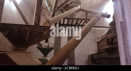Eine alte rostige Reismühle Maschinen Rohr Versorgungswerkzeug ausgesetzt, um den staubigen Hintergrund. Stockfoto