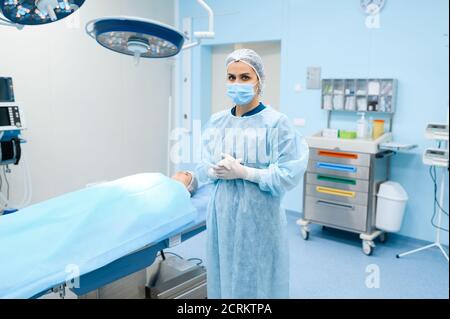 Chirurg im Gewand, Maske und Handschuhe im Operationssaal Stockfoto