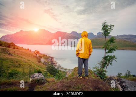 Blick auf den Fjord bei Sonnenuntergang. Ein Mann steht auf einem Felsen und schaut auf den Fjord. Wunderschöne Berglandschaft. Skandinavische Wildnis. Lappland, Natur Stockfoto