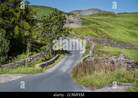 Radfahrerin auf der Straße zwischen Airton und in den Yorkshire Dales, Großbritannien. Stockfoto
