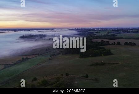 Lebus, Deutschland. September 2020. Der farbenfrohe Morgenhimmel scheint bei Sonnenaufgang über dem Nebel über der Landschaft nahe der deutsch-polnischen Grenze oder (Luftaufnahme mit Drohne). Im Hintergrund sieht man die Stadt Frankfurt (oder). Quelle: Patrick Pleul/dpa-Zentralbild/ZB/dpa/Alamy Live News Stockfoto