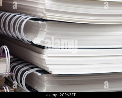 Federgebundene Dokumente. Dokumente, die von einer Feder befestigt sind. Handliche Notizblöcke. Dokumentenstapel. Viele Notizbücher, verschiedene Notizbuchfedern. Stockfoto