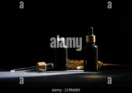 Pipette schwarze Glas Tropfflasche mit goldenen Elementen auf der Dunkler Hintergrund Stockfoto