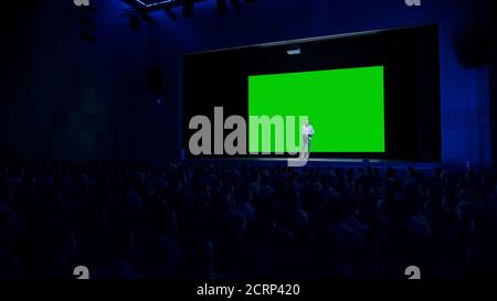 Keynote Speaker macht Präsentation des neuen Produkts für das Publikum, hinter ihm Kino mit Green Screen, Mock-up, Chroma Key. Geschäftskonferenz Stockfoto