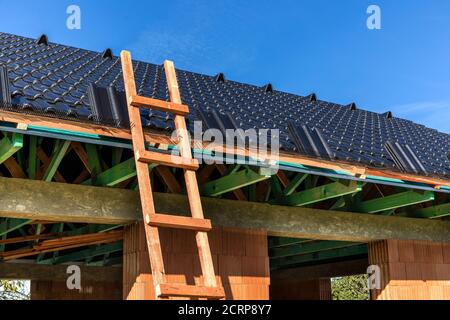 Baustelle Dach schwarze Fliesen. Schwarze Fliesendach auf Wohngebäude Bauhaus. Bau eines Familienhauses. Arbeiten auf dem Dach. Stockfoto