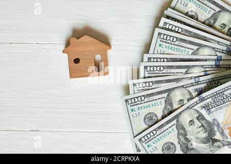 Kleines Holzhaus und hundert Dollar auf weißem Hintergrund Stockfoto