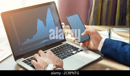 Unkenntlich marketolog arbeiten online, mit Smartphone und Laptop Stockfoto