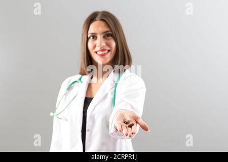 Attraktive türkische Frau Arzt gibt Pillen, hält sie in ihrer Hand in selbstbewusster Stimmung. Stockfoto