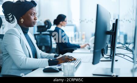 Schöne Ingenieurin, die am Personal Computer in der High-Tech-Industriefabrik arbeitet. Vielbeschäftigter Bürobetrieb in einer Fabrik. Seitenansicht Hochformat Stockfoto