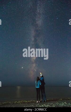 Kerl zeigt Sternenhimmel zu seiner Freundin. Paar beobachten einen Nachthimmel. Astronomischer Hintergrund der Milchstraße. Stockfoto