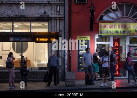 BELGRAD, SERBIEN - 7. SEPTEMBER 2020: Gruppe von Personen, jung und alt, Männer und Frauen, die ihren Bus an einer Haltestelle in Belgrad mit Gesichtsmaske Protective warten Stockfoto