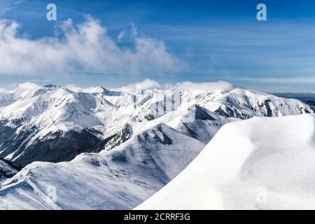 Blick von Kasprowy Wierch auf Kiefernwald mit Winterüberzug im Tal. Schneebedeckte Berggipfel der Tatra, Bukowina Tatrzanska, Polen Stockfoto