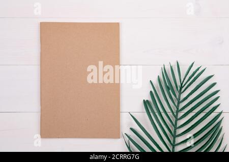 Unbeschriftete Buchumschlagplatz mit Mockup und Blatt auf Holztisch, Poster und Notizbuch, Postkartendekoration Ihr Design oder Branding, Einfachheit und min Stockfoto