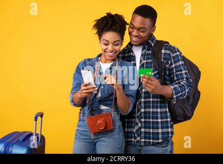 Black Couple Buchung Reisen Tickets Mit Smartphone Über Gelben Hintergrund Stockfoto