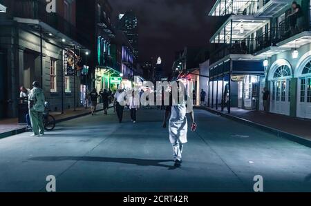 Mann mit Apron geht nachts in Bourbon in Richtung Kamera Straße, New Orleans Stockfoto