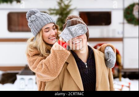 Romantische Blonde Deckende Augen Von Ihrem Freund Während Winter Date Im Freien Stockfoto