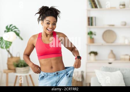 Aufgeregt Frau Trägt Zu Große Jeans Nach Gewichtsverlust Indoor Stockfoto