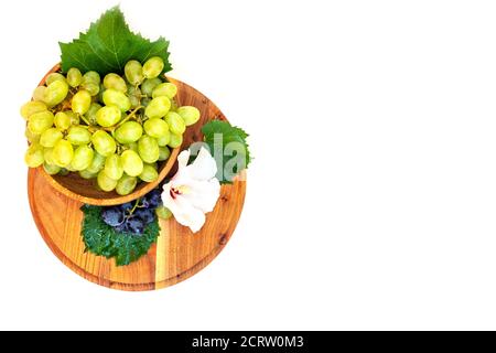 Trauben und Hibiskusblüten auf einem Holzbrett. Weißer Hintergrund. Stockfoto