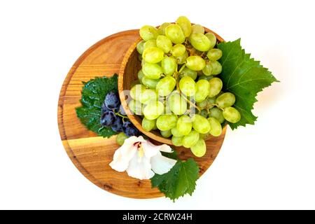 Trauben und Hibiskusblüten auf einem Holzbrett. Weißer Hintergrund. Stockfoto