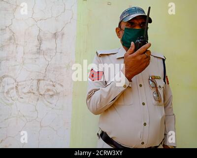 DISTRIKT KATNI, INDIEN - 21. MAI 2020: Ein asiatischer Polizist, der während der Dienstzeit mit einem drahtlosen Walkie-Talkie spricht und Gesichtsmast für Corona-Virus-Pro trägt Stockfoto