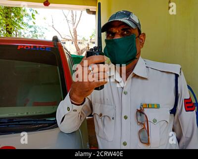 DISTRIKT KATNI, INDIEN - 21. MAI 2020: Ein indischer Polizist, der während der Dienstzeit auf einem drahtlosen Walkie-Talkie mit Gesichtsmast für Corona-Virenschutz spricht Stockfoto