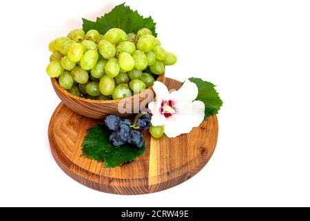 Trauben und Hibiskusblüten auf einem Holzbrett. Weißer Hintergrund. Stockfoto