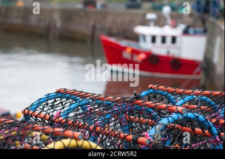 Stapel von Hummertöpfen mit Trawler im Hintergrund, Dunbar Harbour Stockfoto