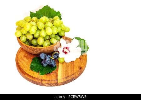 Trauben und Hibiskusblüten auf einem Holzbrett. Weißer Hintergrund. Stockfoto