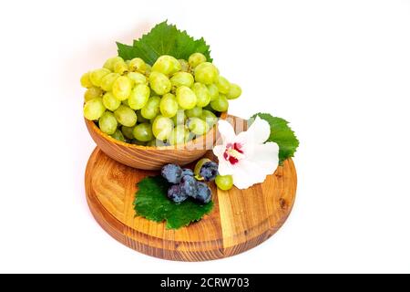 Trauben und Hibiskusblüten auf einem Holzbrett. Weißer Hintergrund. Stockfoto