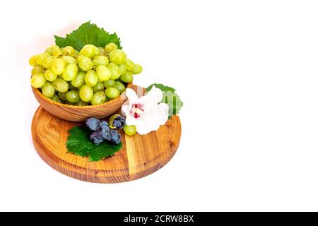 Trauben und Hibiskusblüten auf einem Holzbrett. Weißer Hintergrund. Stockfoto