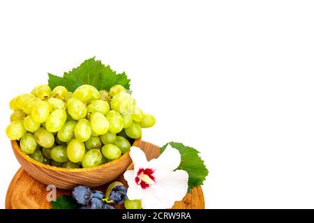 Trauben und Hibiskusblüten auf einem Holzbrett. Weißer Hintergrund. Stockfoto