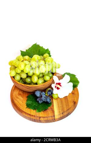 Trauben und Hibiskusblüten auf einem Holzbrett. Weißer Hintergrund. Stockfoto