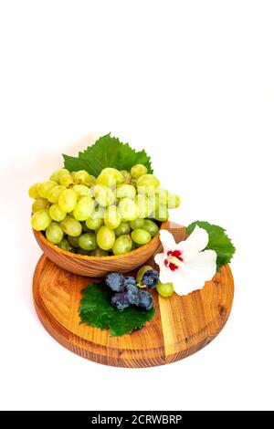 Trauben und Hibiskusblüten auf einem Holzbrett. Weißer Hintergrund. Stockfoto