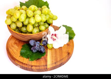 Trauben und Hibiskusblüten auf einem Holzbrett. Weißer Hintergrund. Stockfoto