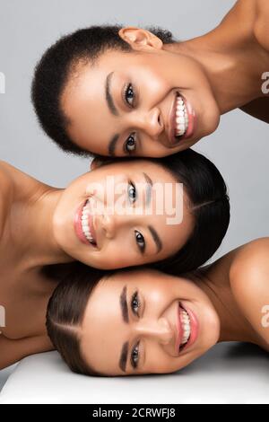 Drei Verschiedene Frauen Posieren Zusammen Lächelnd Auf Grauem Hintergrund, Vertikal Stockfoto