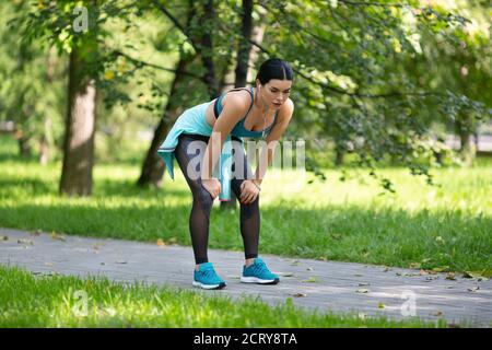 Müde Joggingfrau, die sich nach dem Laufen auf dem Trail ausruhte. Stockfoto