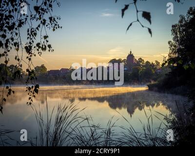 Nach Sonnenaufgang erheben sich Nebelschwaden über dem See Stockfoto