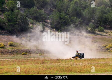 Mann mäht trockene & staubige Weide mit Traktor; Central Colorado; USA Stockfoto